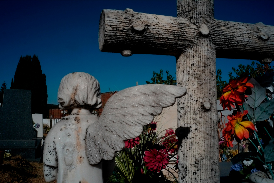 Un ange en beton avec une aile cassée dans un cimetière
