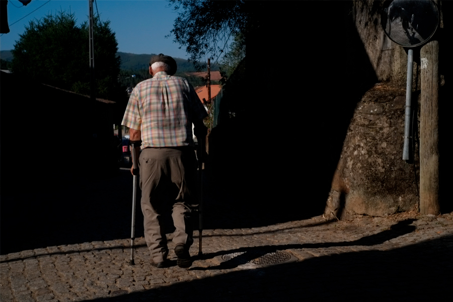 Un vieil homme marchant avec deux béquilles dans une rue du Portugal