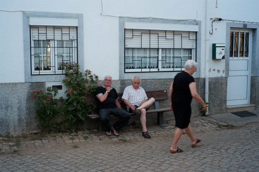 Hommes assis sur un banc, sur la place du village