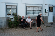 Hommes assis sur un banc, sur la place du village