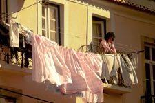 Femme qui étend du linge à sa fenêtre à Lisbonne